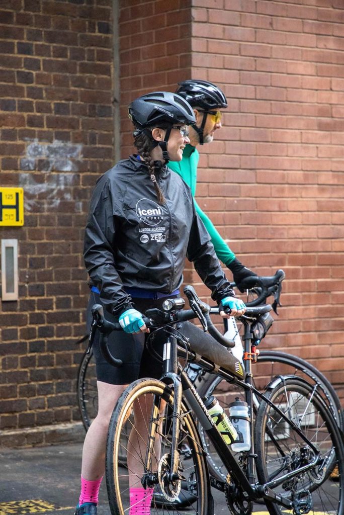 Woman in cycling clothes stands next to her bike 