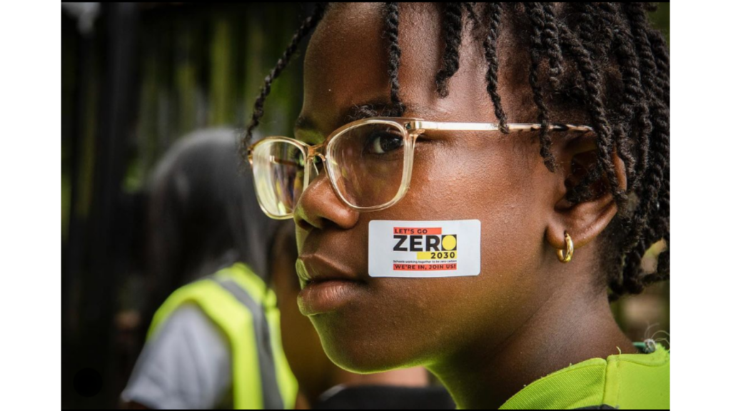 A girl with glasses with a Let's Go Zero sticker on her face