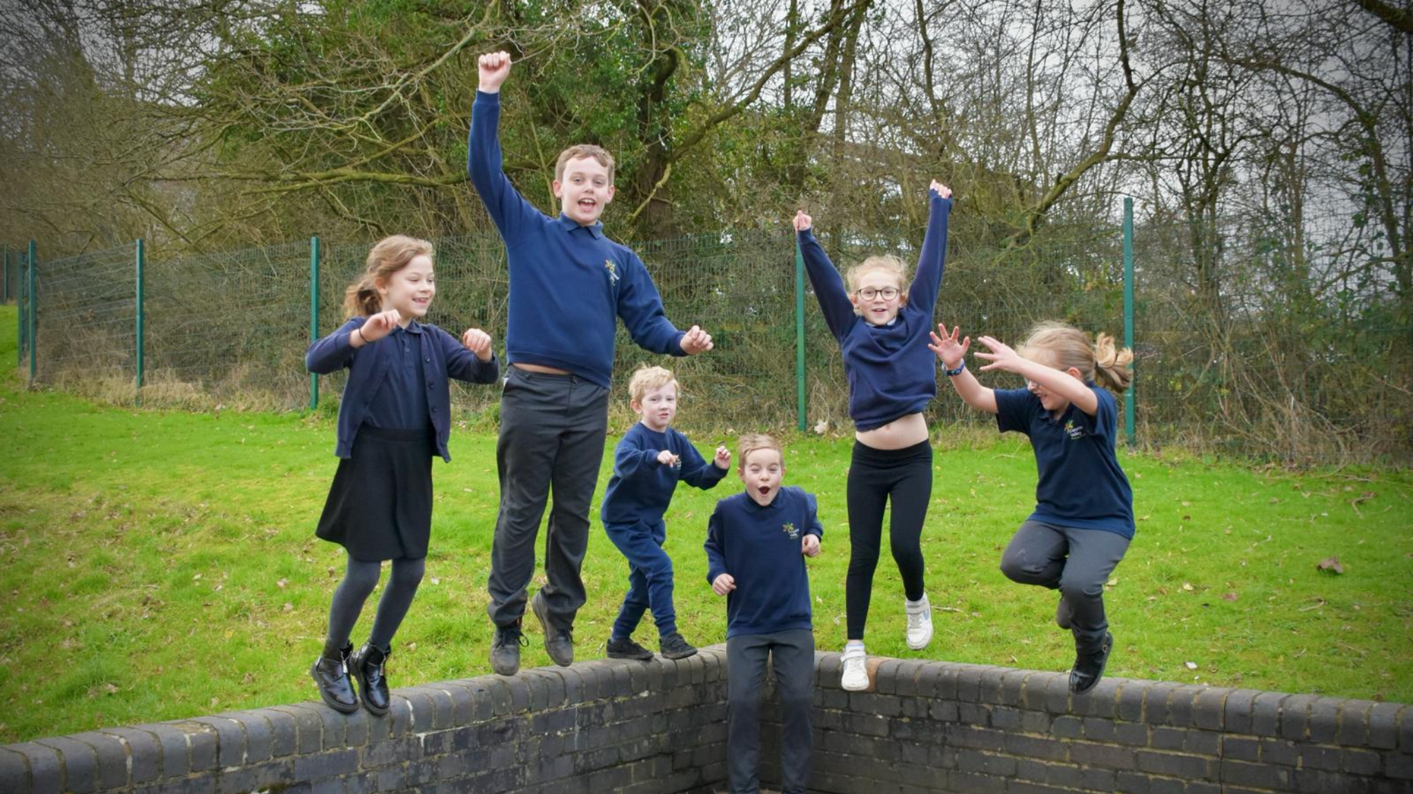 Group of children in school unifrom jumping off a brick wall