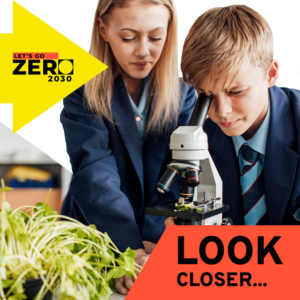 Text reads: Look closer. Two school children are looking through a microscope at a plant.